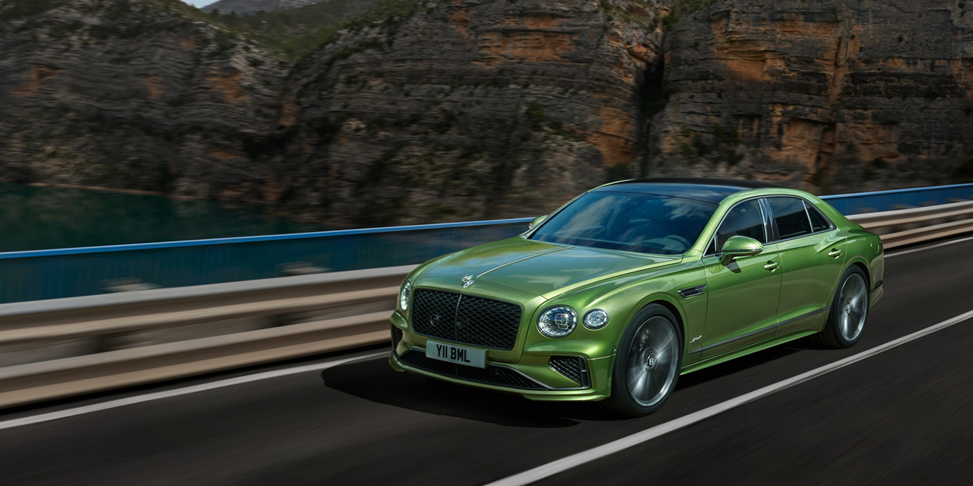 Bentley Luxembourg Bentley New Flying Spur Speed v8 hybrid sedan driving dynamically on a mountain road in Tourmaline Green paint