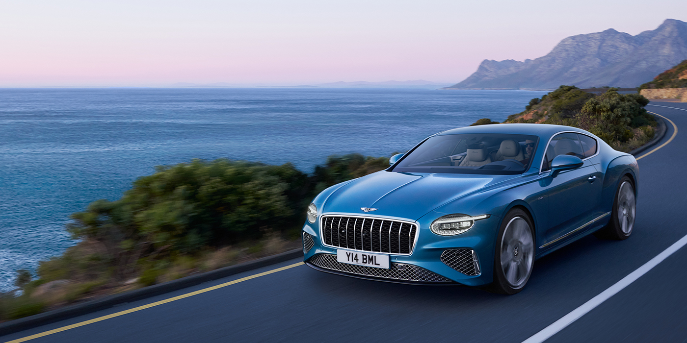 Bentley Luxembourg New Bentley Continental GT Azure coupe in Light Windsor blue paint with 22 inch Azure wheels and chrome grill, driving dynamically by the sea