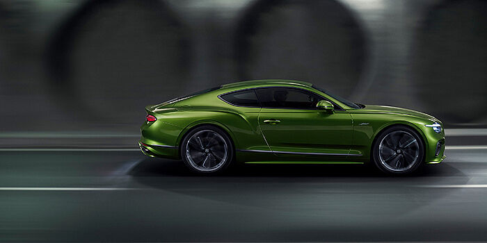  Bentley Luxembourg Bentley Continental GT coupe in Tourmaline Green paint driving in profile on a dark road